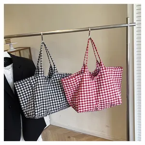 Détail de sacs fourre-tout à carreaux rouges et noirs montrant la texture du tissu tissé