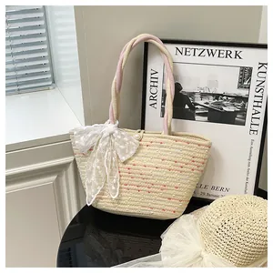 Detalle de bolso de paja trenzada con lazo de encaje blanco y perla estilo rústico francés