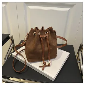 Detail of retro brown suede bucket bag with drawstring closure and golden hardware