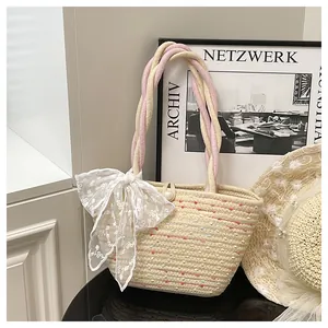 Detalle de bolso de paja tipo cubo con rayas de colores y lazo grande de encaje blanco