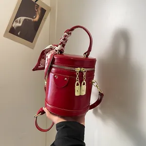 Elegant red faux leather bucket bag with decorative scarf handle and gold hardware detail