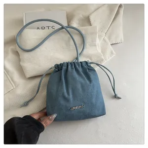 Dettaglio borsa a secchiello in denim azzurro con logo in metallo e coulisse