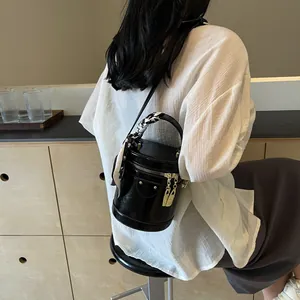 Elegant black leather bucket bag with silk scarf and gold charms on its handle