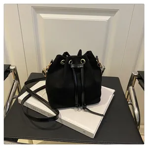 Detail of black textured fabric bucket bag with drawstring closure and golden hardware