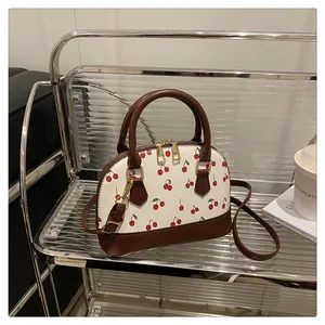 Detailansicht der Muscheltasche mit Kirschmuster, Doppelreißverschluss und Golddekor
