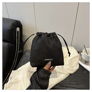 Dettaglio della borsa a secchiello in denim nero con logo JINGPIN e coulisse