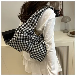 Dettaglio della borsa a tracolla a quadretti bianchi e neri con grande fiocco decorativo