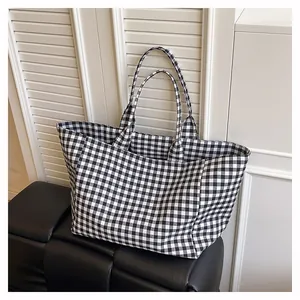 Détail du sac cabas en toile à carreaux sur banc en cuir noir pour un style minimaliste
