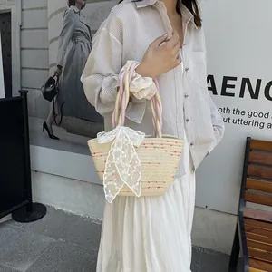 Bolso tipo cubo de paja con asa trenzada rosa y gran lazo de encaje blanco para verano