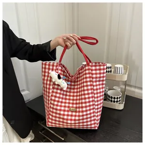 Détail du sac cabas à carreaux rouges et blancs avec peluche de chien et étiquette faite main
