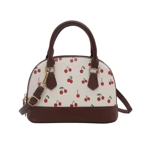Charmante Muschel-Handtasche mit Kirschprint, braunem Lederbesatz und Goldbeschlägen