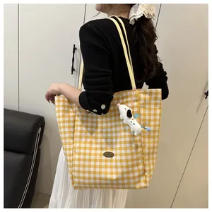 Détail du sac cabas à carreaux jaunes avec pendentif chiot en peluche et logo