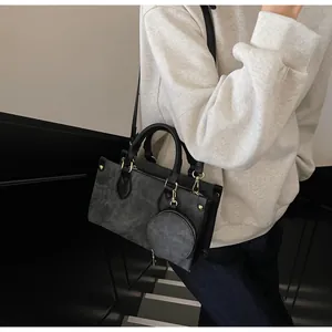 Detail of dark grey matte shoulder bag with gold hardware and round coin purse attachment