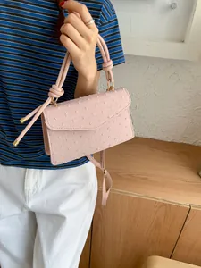 Détail du sac à main rose texturé avec poignée nouée et finitions métalliques dorées