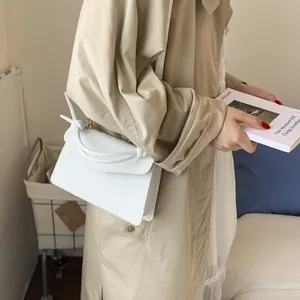 Vue détaillée du sac à main blanc avec poignée nouée et texture de cuir d'autruche