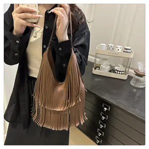 Detailansicht einer braunen Schultertasche mit Fransen im Retro-Boho-Stil am Modell