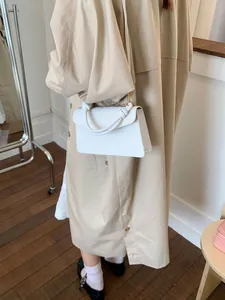Sac bandoulière blanc avec poignée nouée porté sur un trench-coat de couleur kaki