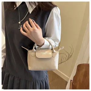 Détail d'un sac à main minimaliste en cuir beige avec anses rondes et texte imprimé