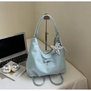 Detail of light blue hobo bag featuring a bow, heart tag, and silver star pendant