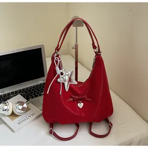 Detail of red large capacity shoulder bag with heart charms and silver star accessory