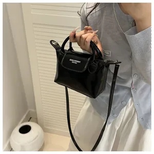 Détail du mini sac en cuir verni noir brillant avec poignée ronde et texte imprimé blanc