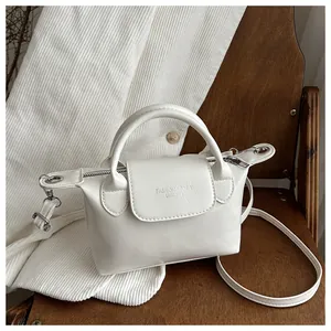 Détail de la texture cuir blanc et lettrage fashion embossé sur un petit sac carré