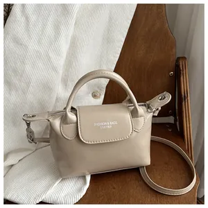 Détail du mini sac beige en cuir PU avec imprimé blanc et accessoires dorés