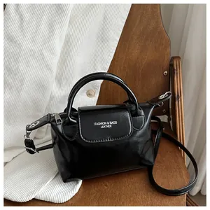 Détail du sac à main en cuir noir brillant sur chaise en bois avec garnitures en métal