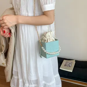 Detail of mint green woven square bucket bag with pearl handle and drawstring closure