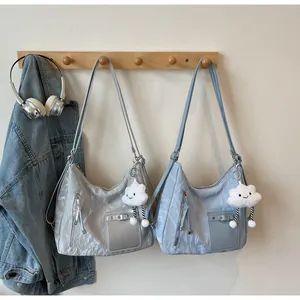 Detail of silver-grey and light blue nylon shoulder bags with metal buckles and plush charms