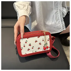 Close-up of red and beige cherry print crossbody bag with a cute cherry charm