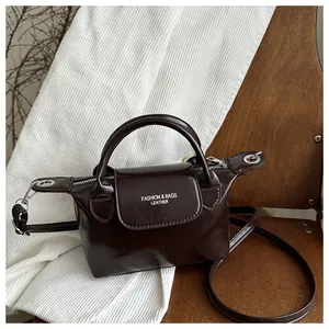 Détail du mini sac en cuir verni marron foncé avec ferrures argentées et bandoulière