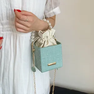 Detail of light green polka dot bucket bag with pearl handle and golden chain strap