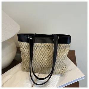 Detail of a chic tote bag featuring black leather and beige woven patchwork texture