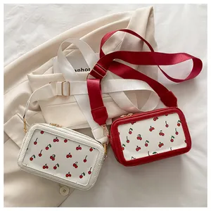 Detalle de bolsos bandolera cuadrados con estampado de cerezas y correa ancha