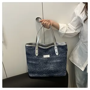 Detail of glittery navy blue denim tote bag with silver leather handles and metallic plate