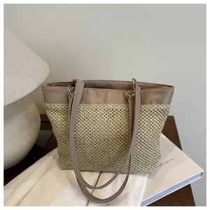 Close-up of woven straw tote bag with brown leather handles and silver ring hardware