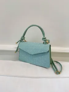 Détail du tissu texturé vert menthe avec ornements touffetés et finitions dorées