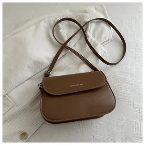 Detailopname van bruine lederen crossbodytas met FANYISSA & BAG logo-opdruk