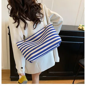 Detail shot of a blue and white striped tote bag with elegant gold chain straps on a model