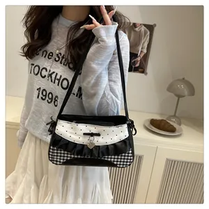 Detail of sweet contrast square bag with gingham pattern and heart pendant charm