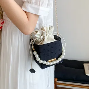 Close-up of contrast bucket bag with oversized pearl handle and gold chain strap detail