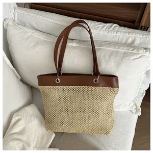 Detail of woven straw tote bag with brown leather handles and smooth texture