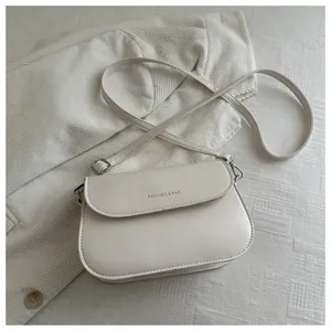Detail van witte PU-lederen crossbodytas met zilveren gespen en tekstlogo