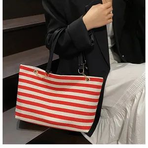 Detail of red and white striped tote bag featuring elegant golden metal chain accents