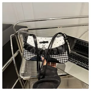 Detailaufnahme von Schleife, Silberherz und Rüschen an der Schultertasche