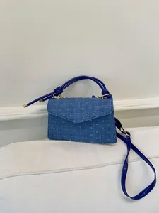 Détail du sac à main en denim bleu avec pois texturés en relief et boucle dorée chic
