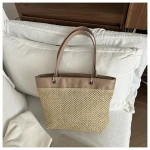 Detail of woven straw tote bag featuring leather straps and metallic silver eyelet accents