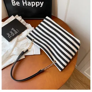 Top view of striped tote bag with gold chain leather strap on a wooden table