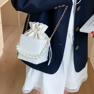 White bucket bag with pearl handle and gold chain strap shown in a lifestyle street shot